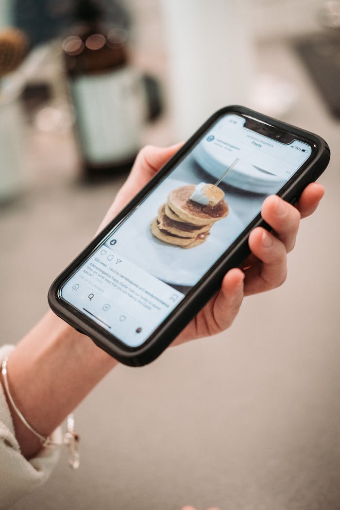 Services Hand holding a smartphone displaying a pancake recipe on a social media app.