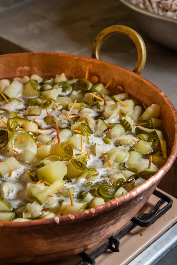 Services Fresh vegetables simmering in a traditional copper pot during cooking.