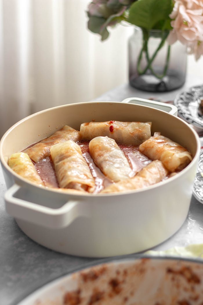 Services Appetizing stuffed cabbage rolls simmering in a pot with a rich sauce.